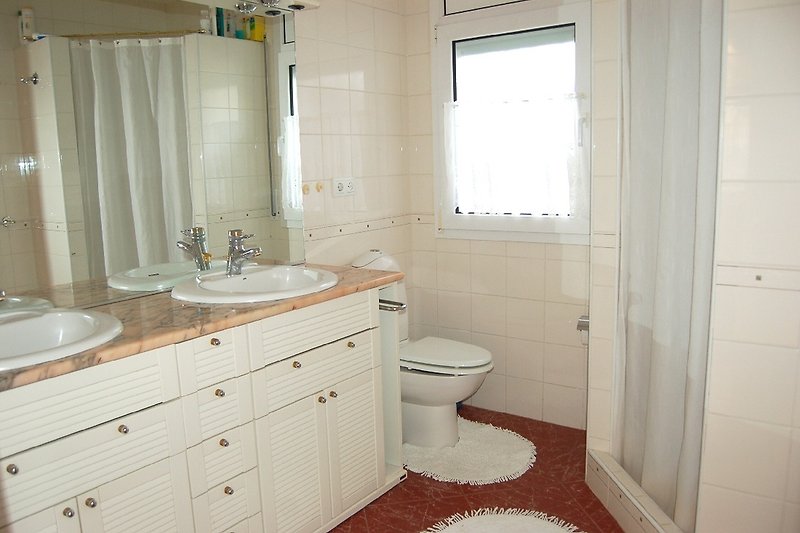 grosses Badezimmer mit Dusche, WC und Doppelwaschbecken – Fenster mit Fliegengitter. Auch eine Waschmaschine ist vorhand