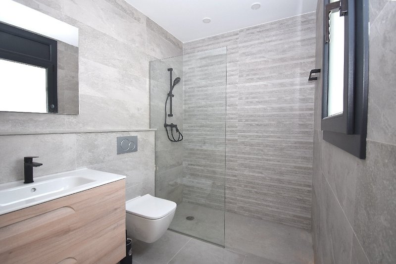 Angeschlossenes Badezimmer mit ebenerdiger Dusche, Waschbecken und WC