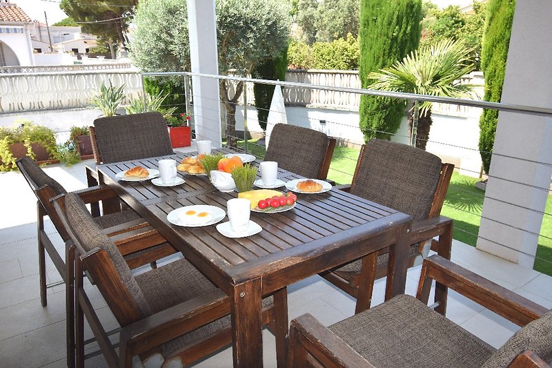 überdachte Terrassenbereich mit Tisch und Stühlen und Grill