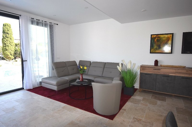 Wohnzimmer mit Leder-Couchgarnitur mit grossem Flachbildschirm. Leseecke mit Sesseln