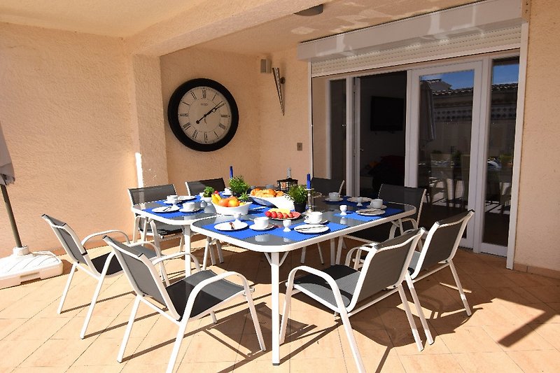 grosse Terrasse ist teilüberdacht mit Tisch, Stühlen, Grill und Sonnenschirm