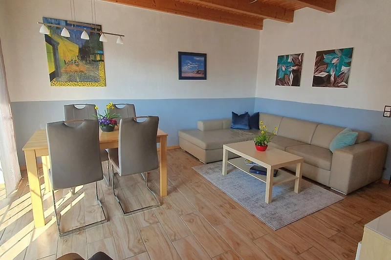 Sitzecke mit Couch, Sessel, Couchtisch und dekorativem Holz.