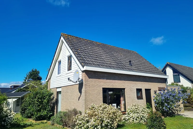 Großzügiges Haus mit gepflegtem Garten, Einfahrt und zwei Autos.