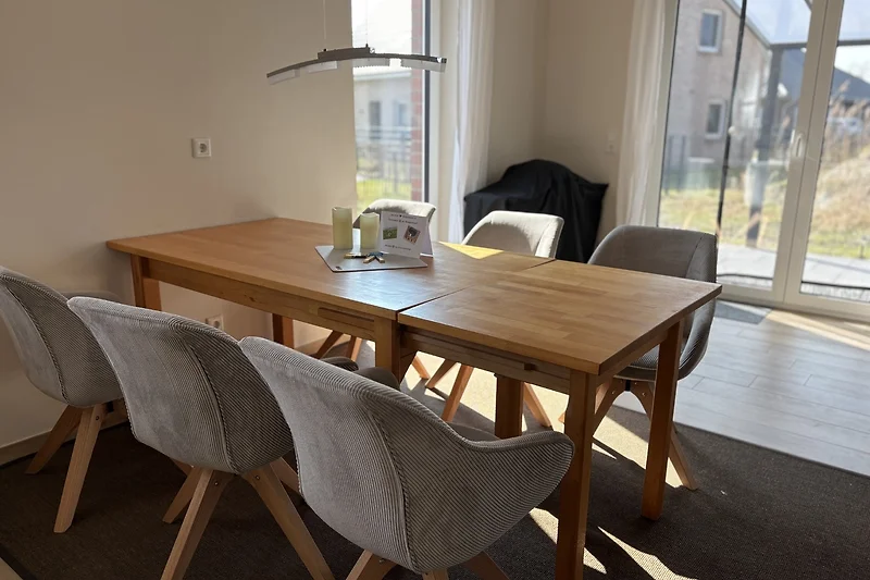 Großer Holztisch mit Armlehnenstühlen, Lampe und Zimmerpflanze.