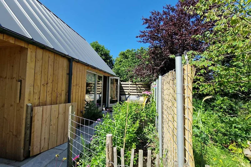 Blockhaus mit Holzfassade, Gartenhaus, Schuppen und grünem Grundstück.