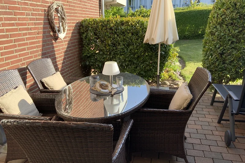 Sitzgruppe und Esstisch auf  Terrasse mit Gartenblick.