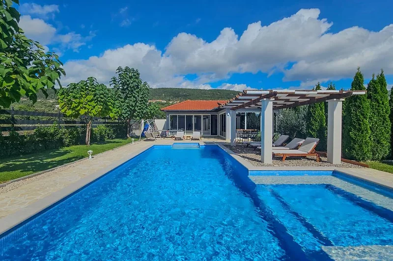 Blauer Pool mit Sonnenliegen, Schirmen und stilvollem Outdoorbereich.