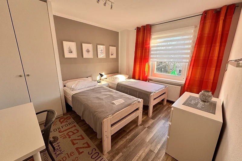 Schlafzimmer mit 2 Einzelbetten, Massivholzmöbeln und frischer Bettwäsche.