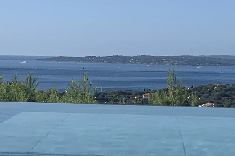 Blauer Pool mit Meerblick, schattigen Plätzen und tropischem Flair.