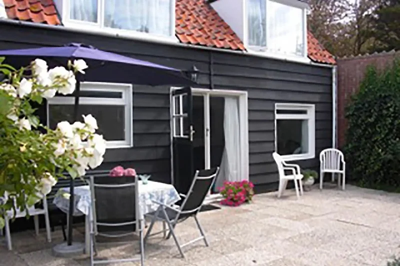 Großer Garten mit Terrasse, Outdoor-Möbeln und blühenden Pflanzen.