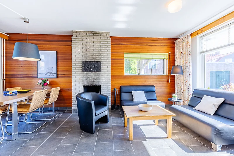 Wohnbereich mit Holzdecke, Sofa, Esstisch, Fernseher und Tageslicht.