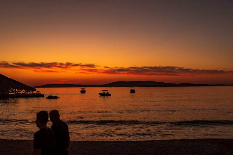 Sonnenuntergang am Meer: Sandstrand, Wellen und Boote genießen!
