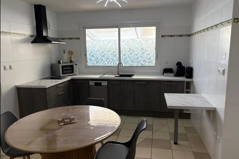 Helle Küche mit Granit-Arbeitsplatte, Gasherd und Essbereich.