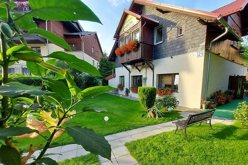 Haus mit großem Garten, gepflegtem Rasen und Einfahrt im Grünen.