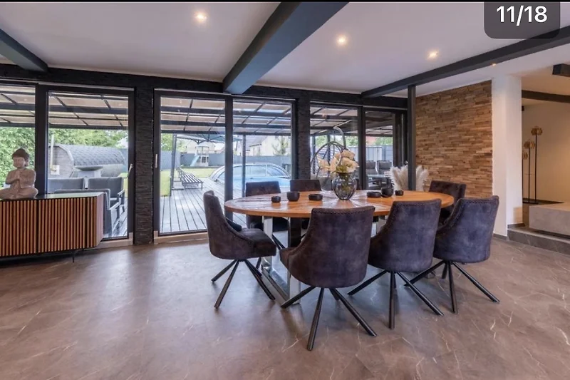 Wohnbereich mit Holzbalken, Designermöbeln und großem Esstisch.