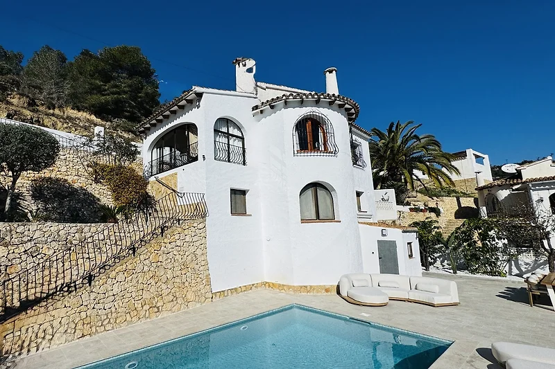 Weitläufige Villa mit Pool, Palmen und Balkon im sonnigen Wohngebiet.