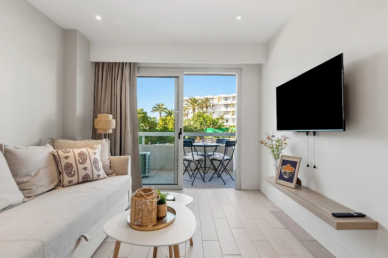 Penthouse-Wohnzimmer mit Couch, Daybed, Kissen und Balkonmöbeln.