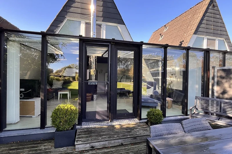 Sonnige Terrasse mit Outdoor-Möbeln, Pflanzen und markanter Architektur.