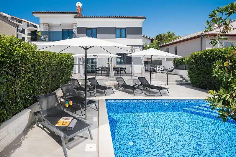Pool mit Sonnenliegen, Schirmen und Outdoor-Möbeln für entspannte Stunden.