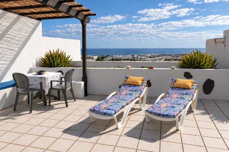 Terrasse mit Meerblick, ausgestattet mit bequemen Sonnenliegen und Essbereich im Freien