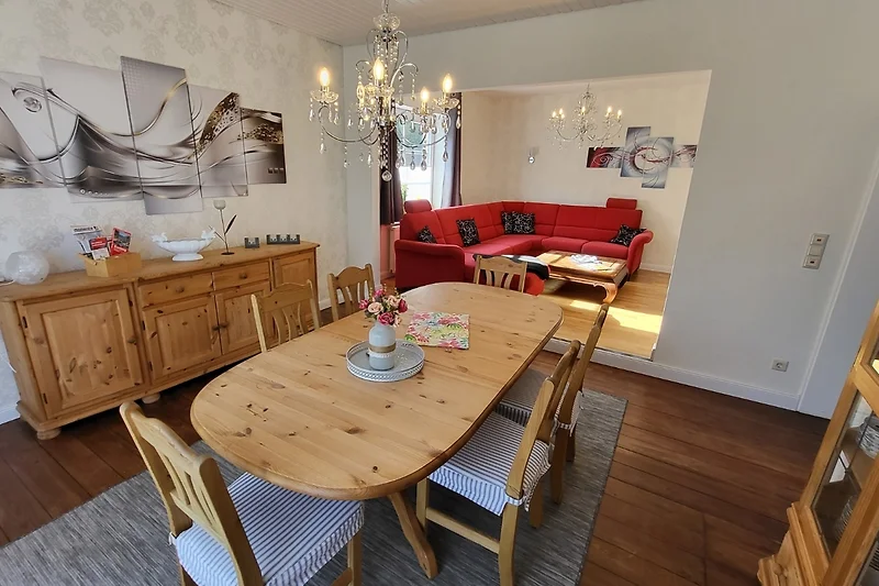 Essbereich mit Sideboard, Hängelampe, Sessel und dekorativem Rahmen.