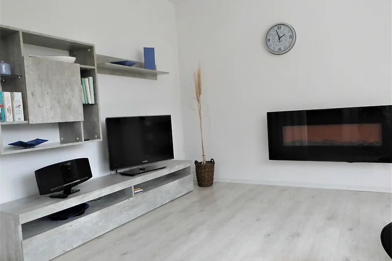 TV-Wand und Elektrokamin prägen das Wohnzimmerdesign.