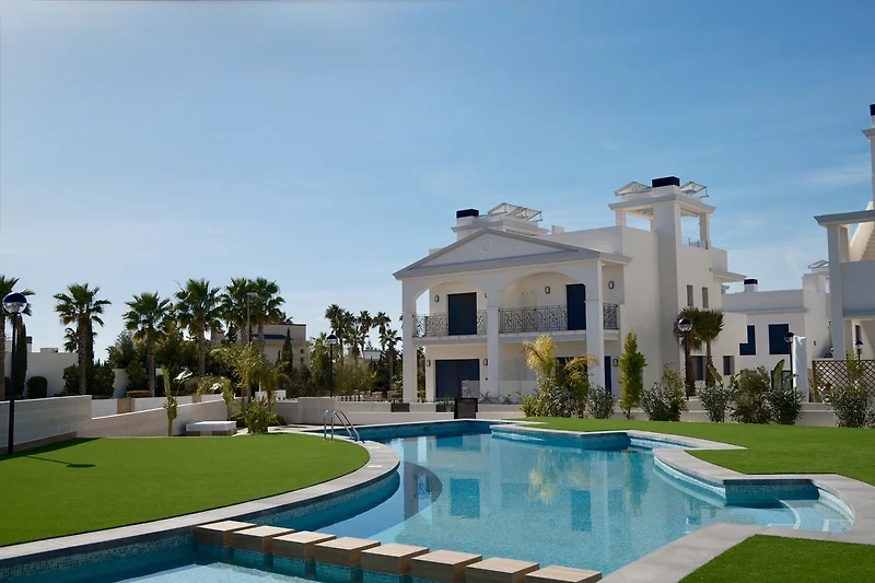 Pool mit Palmen, Wasserspiel und gepflegtem Garten im Resort-Ambiente.