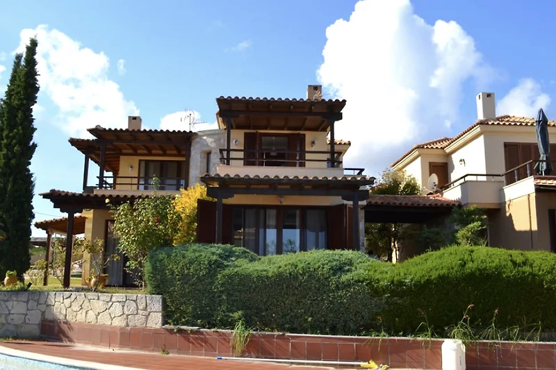 Villa mit Balkon, Palmen und gepflegtem Garten in ruhiger Wohnlage.