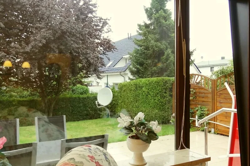 Sonnige Terrasse mit Gartenmöbeln, gepflegtem Garten und Blick ins Grüne