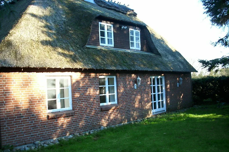 Traditionelles Reetdach, Sprossenfenster und Bauernhaus-Charakter.