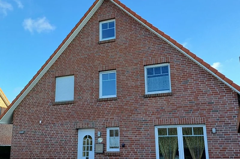 Backsteinhaus mit Sprossenfenstern, gepflegter Fassade und Parkplatz.