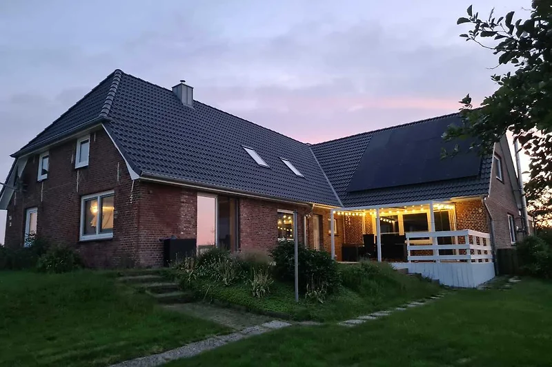 Großzügiges Haus mit Solarpanel, gepflegtem Rasen und Einfahrt.