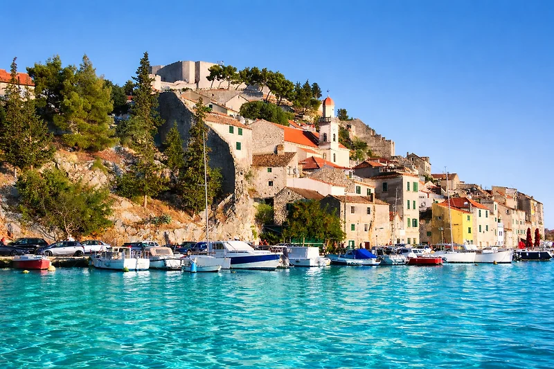 Weitläufige Bucht mit Yachthafen, Motorbooten und türkisfarbenem Wasser.