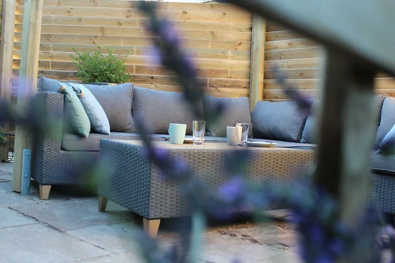 Entspannen Sie auf Holzterrasse mit Gartenmöbeln und blühenden Pflanzen.