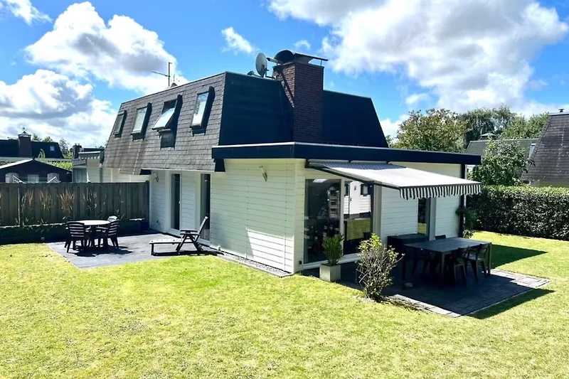 Geräumiges Haus mit markantem Dach, Einfahrt und schattigem Vorbau.