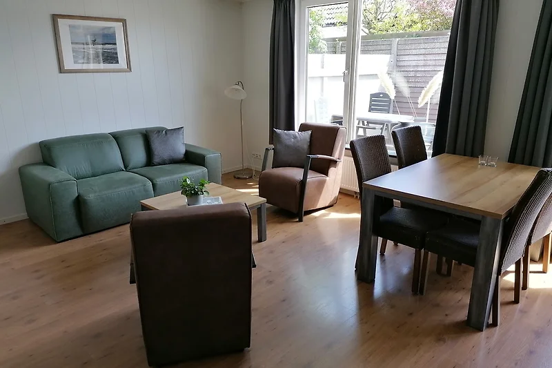Großzügiges Wohnzimmer mit Sofa, Esstisch, Pflanzen und TV.