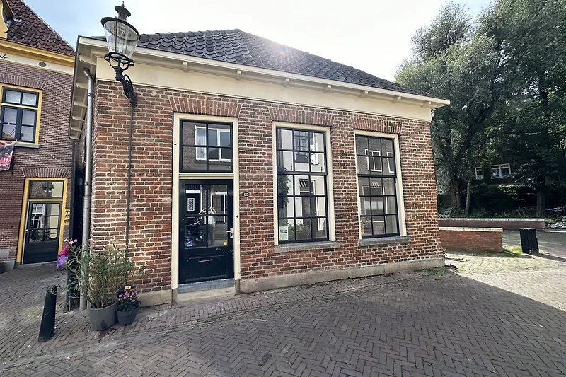 Fahrradstellplatz vor Backsteinfassade mit Fenster und Eingangstür.