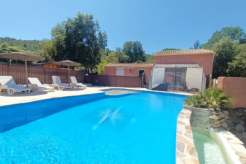 Pool mit Sonnenliegen, Schirmen und Outdoor-Lounge im Resort-Stil.