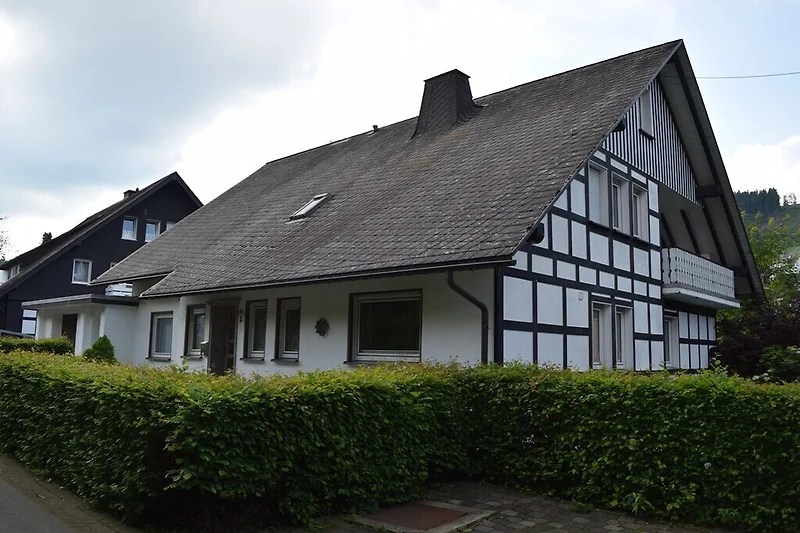 Historisches Haus mit grauer Fassade, Sprossenfenstern und großem Garten.