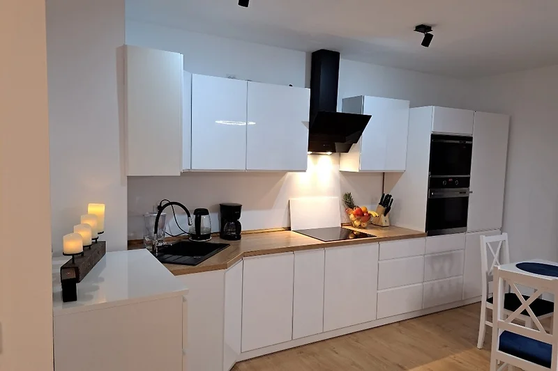 Offene Küche mit Holzdetails, Esstisch und viel Stauraum.