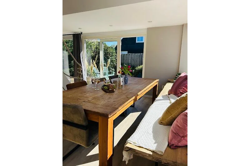 Helles Esszimmer mit Holztisch, bequemen Stühlen und Pflanzen.