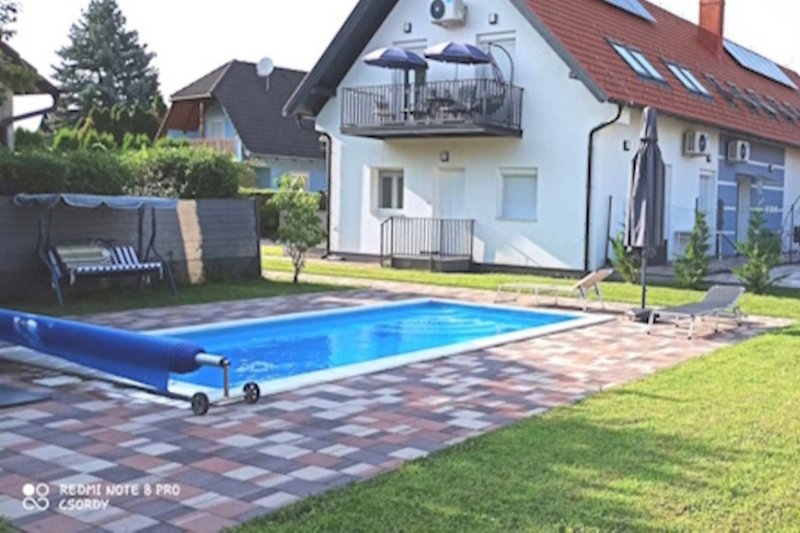 Geräumiger Garten mit Pool, Bäumen und gemütlicher Terrasse.