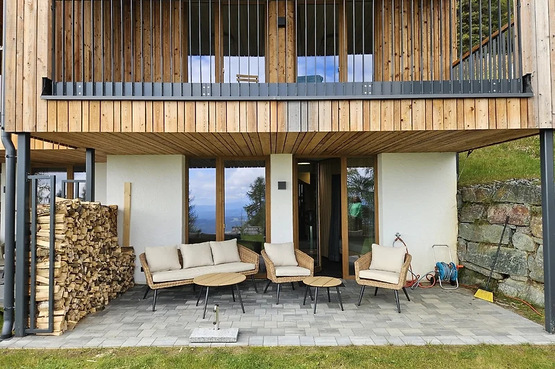 Großzügige Terrasse und Naturholz-Fassade mit überdachtem Eingang.