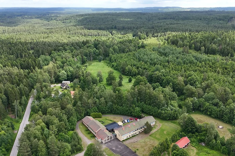 Luftaufnahme: Felder, Plantagen und ein Dorf im grünen Umland.