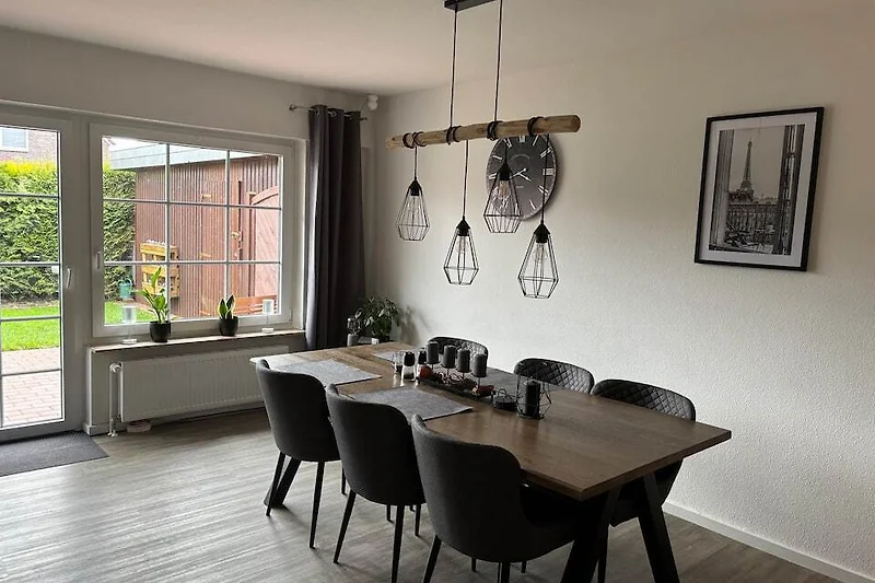 Großer Esstisch, markante Holzdecke und stilvolle Hängeleuchte.