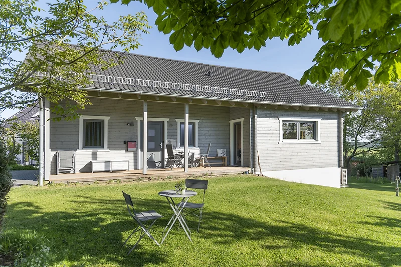 Großes Haus mit Garten, gepflegtem Rasen und überdachter Veranda.