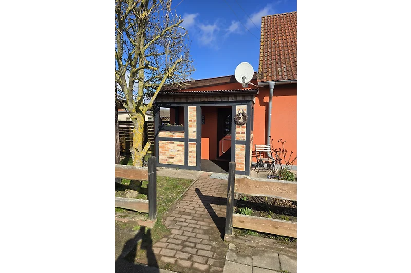 Holztür mit Ziegelmauer, schattigem Durchgang und stabilem Tor.