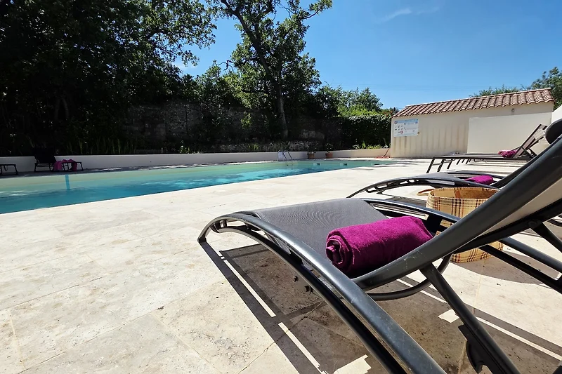 Poolbereich mit Sonnenliegen, Schirmen und wetterfesten Sitzmöbeln.