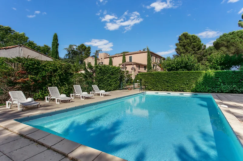Palmen, Pool und stilvolle Sonnenliegen im begrünten Innenhof.