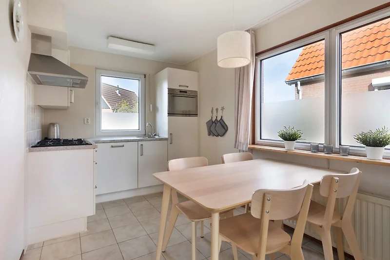 Offene Wohnküche mit Massivholztisch, Designerlampen und Hauspflanze.